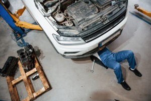 Artificial lighting. Employee in the blue colored uniform works in the automobile salon.