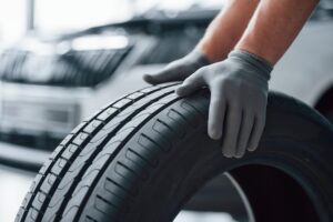 hands-only-mechanic-holding-tire-repair-garage-replacement-winter-summer-tires-min
